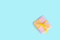 Top view of a gift box wrapped in pink dotted paper and tied yellow bow over light blue background. Royalty Free Stock Photo