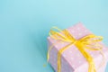 Top view of a gift box wrapped in pink dotted paper and tied yellow bow over light blue background. Royalty Free Stock Photo