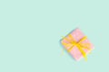 Top view of a gift box wrapped in pink dotted paper and tied yellow bow over light blue background. Vintage effect. Royalty Free Stock Photo