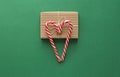 Top view. Gift Kraft Brown Color Box and Candy Canes Red and White in Heart Shape Lies on the Green Background, View From the Top Royalty Free Stock Photo