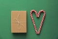 Top view. Gift Kraft Brown Color Box and Candy Canes Red and White in Heart Shape Lies on the Green Background, View From the Top Royalty Free Stock Photo