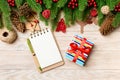 Top view of gift, notebook, Christmas toys, decorations and fir tree branches on wooden background. New Year holiday