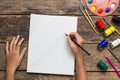 Top view of Girl hand drawing empty paper and colorful pencils, child painting using watercolors and paint brush on old wooden tab Royalty Free Stock Photo