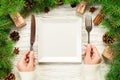 Top view girl holds fork and knife in hand and is ready to eat. Empty white square plate on wooden christmas background. holiday Royalty Free Stock Photo