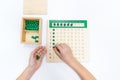 Top view of girls hand is sorting a puzzle of colored plastic beads in montessori school Royalty Free Stock Photo