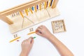 Top view of girls hand is sorting a puzzle of colored wooden geometric shapes in montessori school Royalty Free Stock Photo