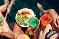Top view. Girls in swimsuits eat fruits and drink cocktails in swimming pool in summertime.