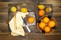 Top view of glass bottle of fresh orange juice with fresh fruits in basket and flowers vase on wooden planks table. Royalty Free Stock Photo