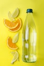 Top view of glass bottle of fresh water with citrus.Slices of lemon and orange, glass bottle of drink on the yellow background Royalty Free Stock Photo