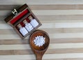 Top view of Glass Bottles of homeopathic pills in a retro styled on old wooden box and globules in wood spoon on wood background