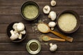 Top view of glass bowl of oil, ceramic bowls full of rice, mushrooms, rosemary, wooden spoons on the rustic table Royalty Free Stock Photo