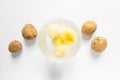 Top view of glass bowl with water and peeled potatoes and raw unpeeled potato vegetables. White background. Royalty Free Stock Photo