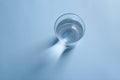 Top view of a glass of clean drinking water on blue background