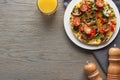 Top view of glass of juice and tasty omelet with vegetables for breakfast on wooden table with pepper and salt. Royalty Free Stock Photo