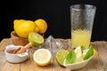 Top view of glass with lemonade, lemon wedges, lime, brown sugar, juicer and wooden bowl with lemons, black background, Royalty Free Stock Photo