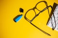 Top view of glasses, keyboard and a blue marker on a yellow work table Royalty Free Stock Photo