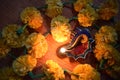 Top view of glowing lit colorful conch shaped diya around marigold on occasion of Diwali festival