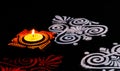 Top view of glowing terracotta lamp with beautiful white and red rangoli art on black background. diwali concept Royalty Free Stock Photo