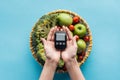 Top view of glucometer in female hands with vegetables and apples Royalty Free Stock Photo