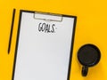 Top view goals list with notebook, cup of coffee on yellow background with blank space for text. Flat lay. Copy space. Royalty Free Stock Photo