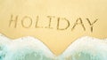 Top view of golden sand and soft wave with handwritten HOLIDAY text. Abstract summer vacation concept