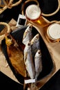 Smoked gutted bream, salted dried roach and sabrefish on wooden board with foamy light beer