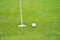 Top view of a golf ball on green course at hole. Golf ball and golf club on green in the evening golf course with sunshine Royalty Free Stock Photo