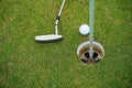 Top view of a golf ball with putter on green course at hole. Golf ball and golf club on green in the evening golf course with Royalty Free Stock Photo