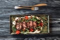 top view of gourmet sliced New York steak, vegetables and fork with knife