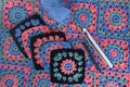 Top view of granny squares, crochet hooks of different sizes