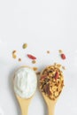 Top view granola and yogurt in wooden spoons on white background, vertical idea for banner with copy space