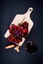 top view of grape on cutting board with red wine in glass and corks with corkscrew on black background 1 Royalty Free Stock Photo