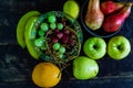Top view of the grapes in the bowl with other delicious fruits on the wooden surface Royalty Free Stock Photo