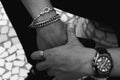 Top view grayscale shot of a mans hands decorated with a bracelet, watch, and rings