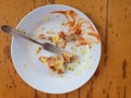 Greasy plate with lonely fork, bread and omelette leftovers