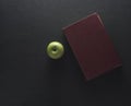 Top view Green apple with old book on black wood background. Sch Royalty Free Stock Photo