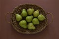 Green pears in the basket on terracotta background