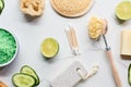 Top view of green bath salts, body brush, loofah, bath sponge and pumice stone near fresh lime and cucumber on marble Royalty Free Stock Photo