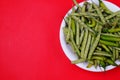 Top view of green beans and chili pepper on plate isolated on red background Royalty Free Stock Photo