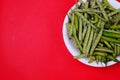 Top view of green beans and chili pepper on plate isolated on red background Royalty Free Stock Photo