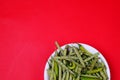 Top view of green beans and chili pepper on plate isolated on red background Royalty Free Stock Photo