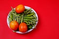 Top view of green beans, chili pepper, and tomatoes on plate isolated on red background Royalty Free Stock Photo