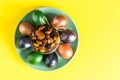 Top view of a green ceramic plate with An Easter cake and painted eggs on a yellow background Royalty Free Stock Photo