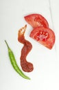 Top view of green chili pepper, slices of tomato and hot tomato sauce