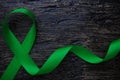 Top view of green color ribbon on dark background. Gall bladder and bile duct cancer, mental health, cerebral palsy awareness