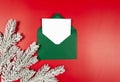 Top view of green envelope, white card and fir tree branches on red background. Royalty Free Stock Photo