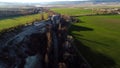 Top view of green fields and rock wall. Shot. Panoramic view of natural stone wall with trees on background of houses