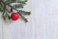 Top view of a green fir branch with a red shiny Christmas ball on a wooden background. Royalty Free Stock Photo
