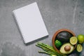 Top view green fresh healthy vegetables in wooden plate and blank notebook on gray background