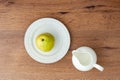 Top view of green pear on a white ceramic plate and empty milk jug on wooden table Royalty Free Stock Photo